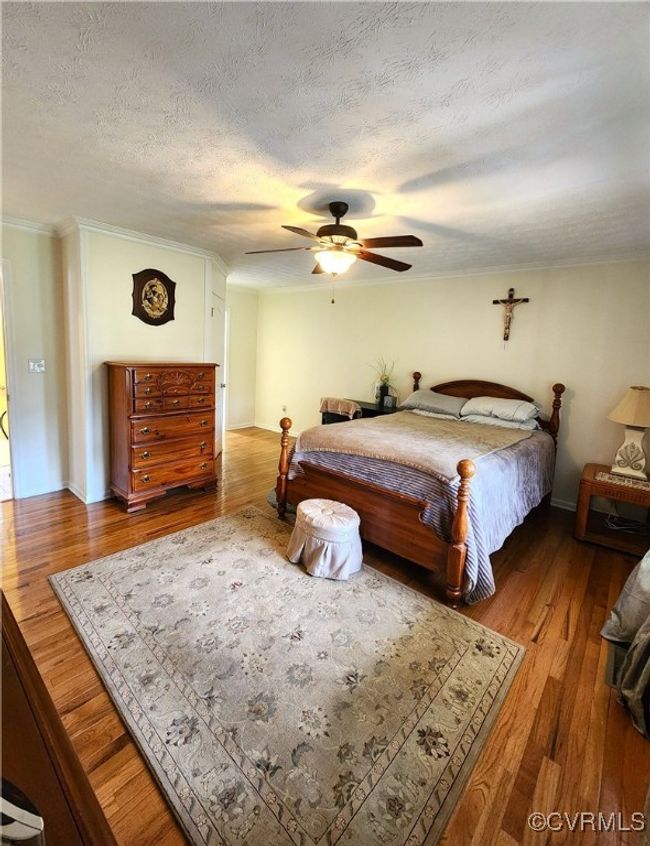 Bedroom with wood finished floors, ornamental molding, ceiling fan, and a textured ceiling | Image 15