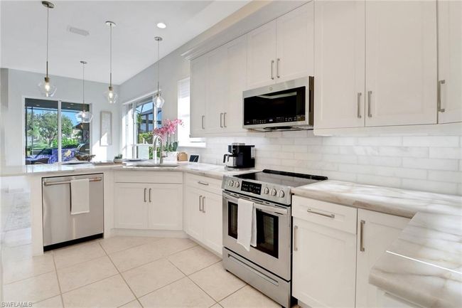 Kitchen with a peninsula, tasteful backsplash, a sink, decorative light fixtures, and stainless steel appliances | Image 10