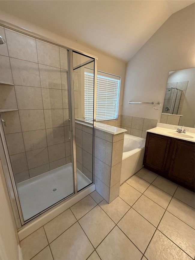 Full bath featuring vanity, a stall shower, tile patterned floors, lofted ceiling, and a garden tub | Image 10