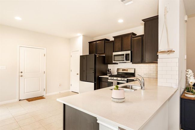 Kitchen featuring appliances with stainless steel finishes, light countertops, decorative backsplash, dark brown cabinetry, and recessed lighting | Image 14