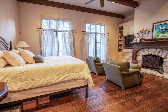 Bedroom with dark wood-style floors, a fireplace, ceiling fan, and beamed ceiling | Image 12