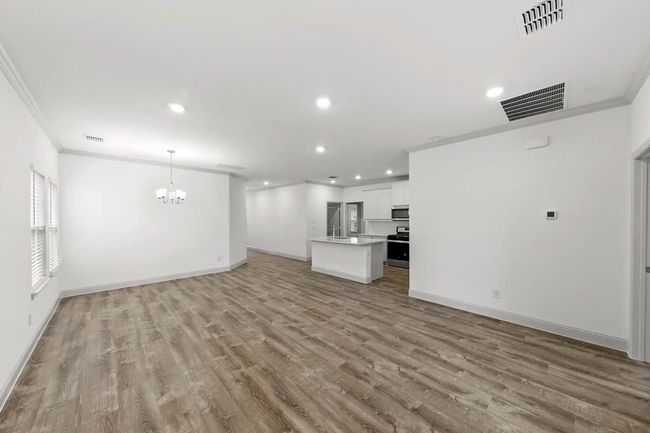 Unfurnished living room with ornamental molding, wood finished floors, a chandelier, and recessed lighting | Image 5