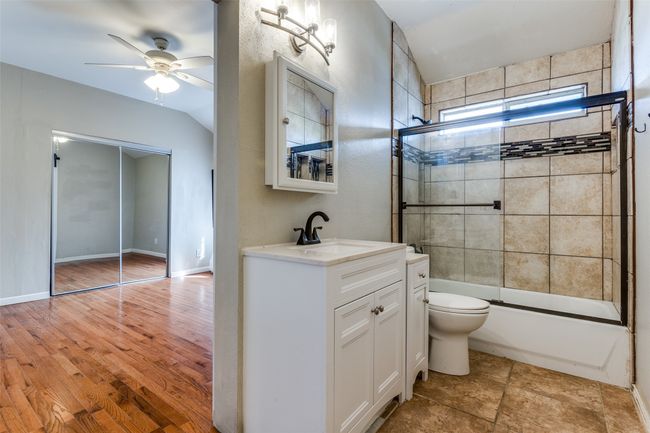 Bathroom with vanity, a ceiling fan, baseboards, shower / bath combination with glass door, and toilet | Image 22
