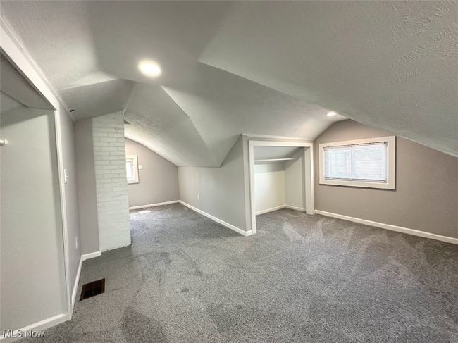 Bonus room featuring a textured ceiling, visible vents, carpet floors, baseboards, and vaulted ceiling | Image 11