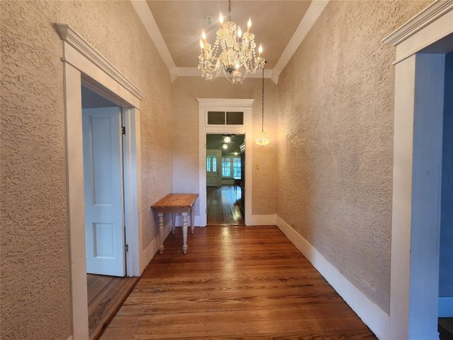 Hallway featuring a textured wall, wood finished floors, and a chandelier | Image 10