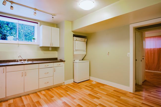 Kitchen with light wood-style flooring, a sink, stacked washer / dryer, and rail lighting | Image 25