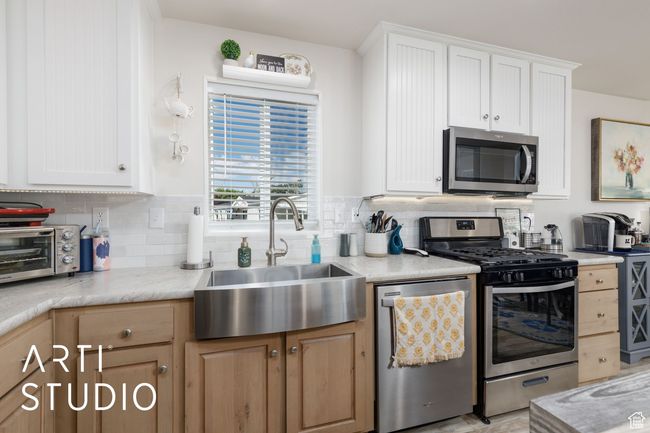 Kitchen featuring stainless steel appliances, tasteful backsplash, and white cabinets | Image 13