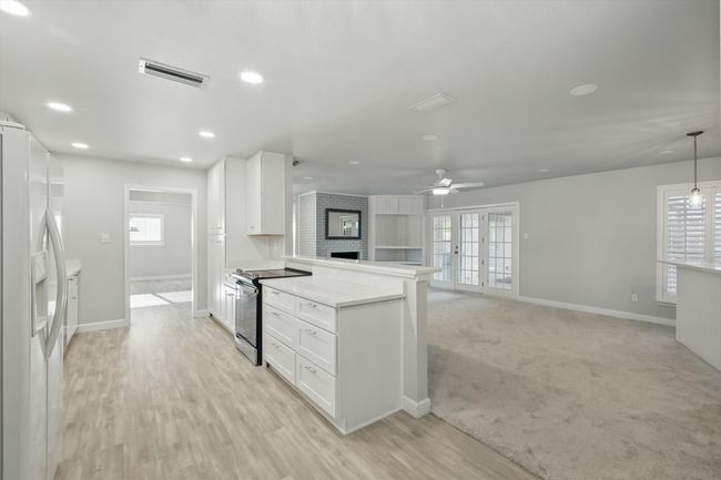Kitchen featuring range with electric stovetop, baseboards, a peninsula, white refrigerator with ice dispenser, and ceiling fan | Image 7