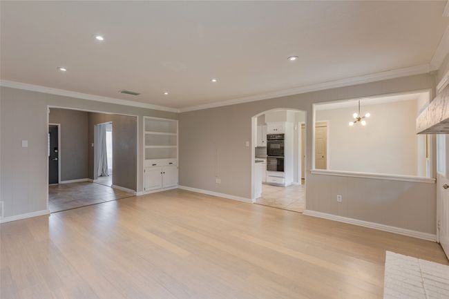 Unfurnished living room featuring arched walkways, ornamental molding, light wood-type flooring, a chandelier, and recessed lighting | Image 7