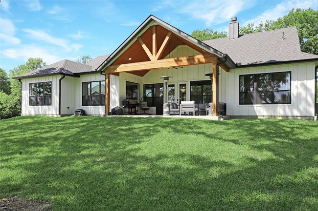 Back of house with a chimney, a yard, board and batten siding, and a shingled roof | Image 34