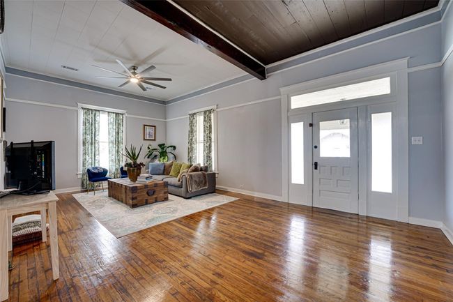 Living area featuring a ceiling fan, hardwood / wood-style floors, baseboards, beam ceiling, and visible vents | Image 9