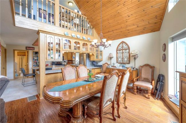 Dining space with high vaulted ceiling, a chandelier, wooden ceiling, and light wood-style floors | Image 10