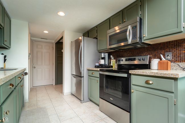 kitchen with green cabinets, appliances with stainless steel finishes, light countertops, light tile patterned floors, and recessed lighting | Image 14