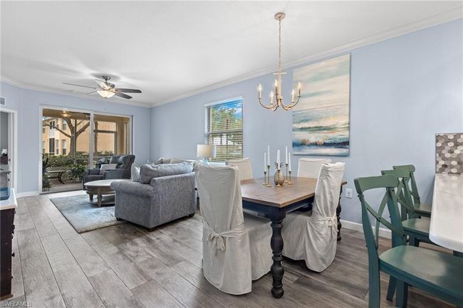 Dining area featuring lvp wood style flooring, ceiling fan with notable chandelier, and crown molding | Image 9