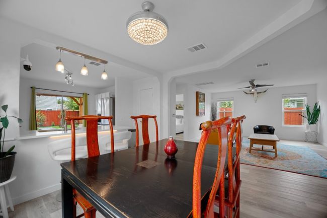 Dining area featuring light wood-style flooring, healthy amount of natural light, a chandelier, and a ceiling fan | Image 14