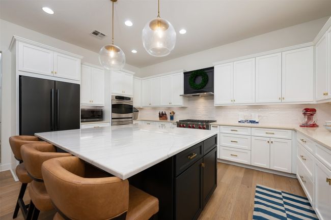 A kitchen island with quartzite countertop and extra seating. | Image 11