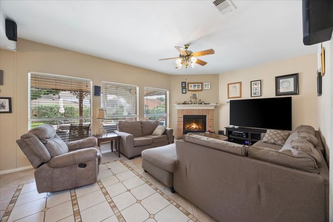 Living area featuring ceiling fan, a fireplace, light tile patterned floors, and baseboards | Image 17