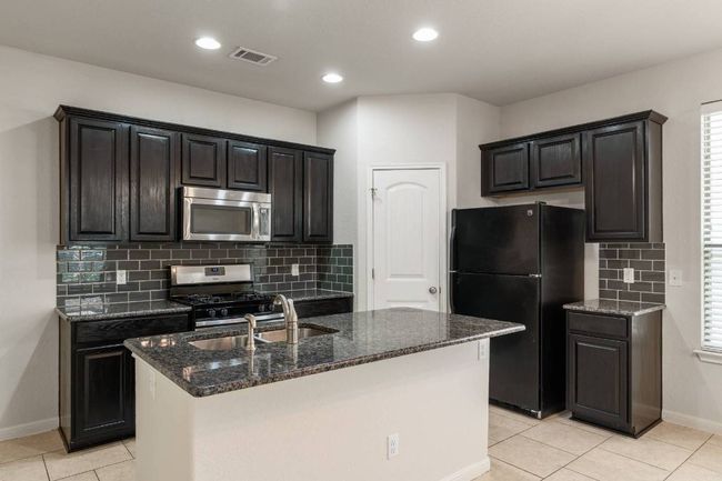 The gourmet kitchen is a chef’s delight, showcasing a central island with bar seating. | Image 16