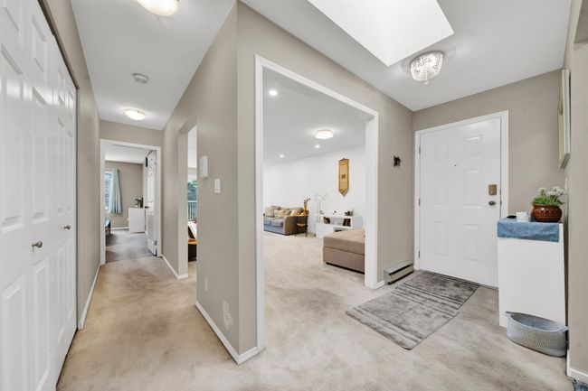 Foyer featuring a skylight, baseboards, a baseboard heating unit, and light colored carpet | Image 14