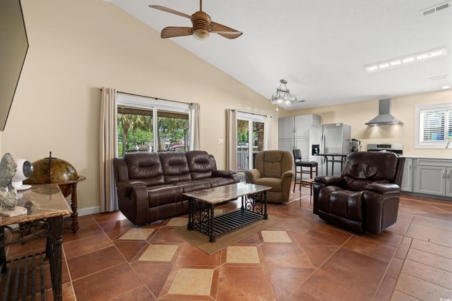 Living room with healthy amount of natural light, ceiling fan, a chandelier, high vaulted ceiling, and dark tile patterned flooring | Image 19