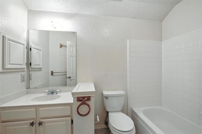 Full bathroom with a textured ceiling, vanity, and a textured wall | Image 29