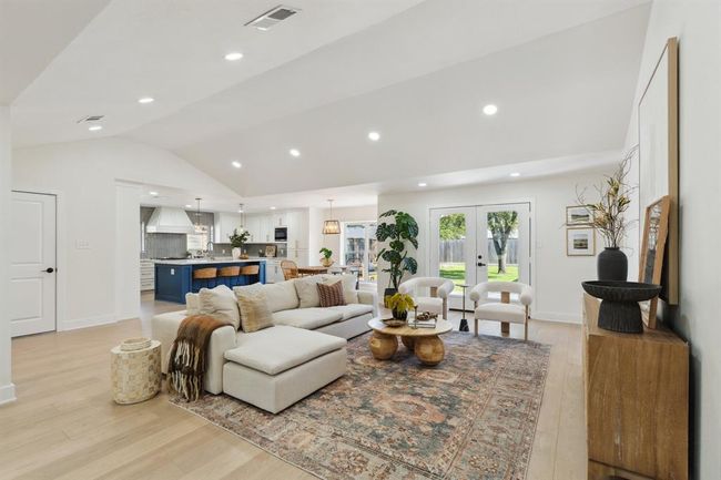 The living room unfolds in a spacious open-concept layout, seamlessly flowing into the adjacent kitchen and dining areas. | Image 9