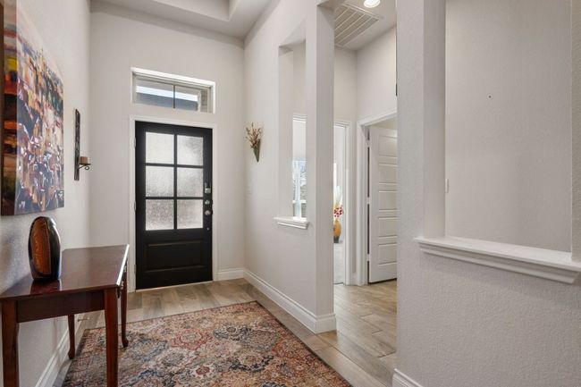 Entrance foyer with a high ceiling, baseboards, visible vents, and wood finish floors | Image 8