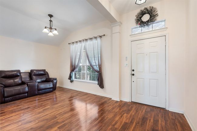 Entryway featuring baseboards, lofted ceiling, an inviting chandelier, and wood finished floors | Image 8