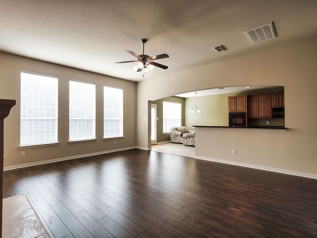 Unfurnished living room featuring ceiling fan, wood finished floors, baseboards, and a chandelier | Image 25