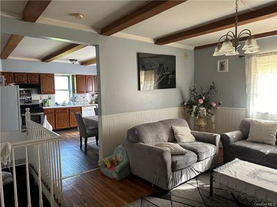 Living room with ornamental molding, dark hardwood / wood-style flooring, a notable chandelier, and beam ceiling | Image 2