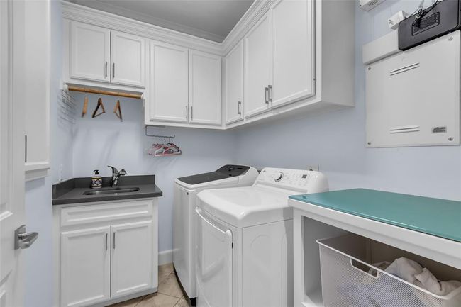 The second-floor laundry room features a sink, ample storage, and includes both the washer and dryer. | Image 26