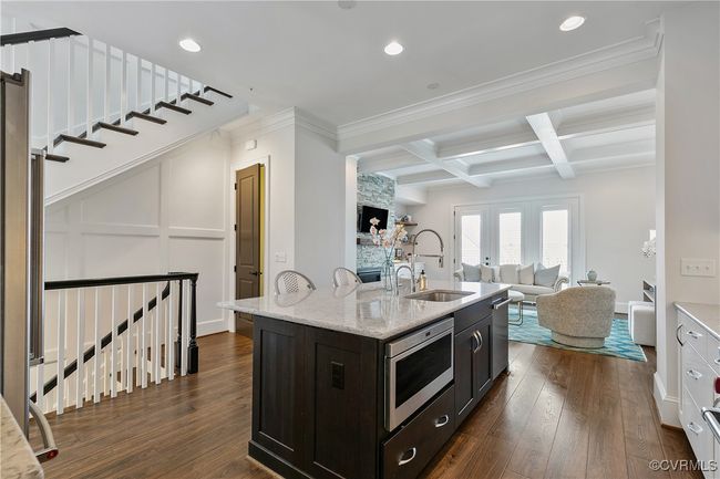 Kitchen with dark wood-type flooring, a sink, an island with sink, coffered ceiling, and beamed ceiling | Image 10