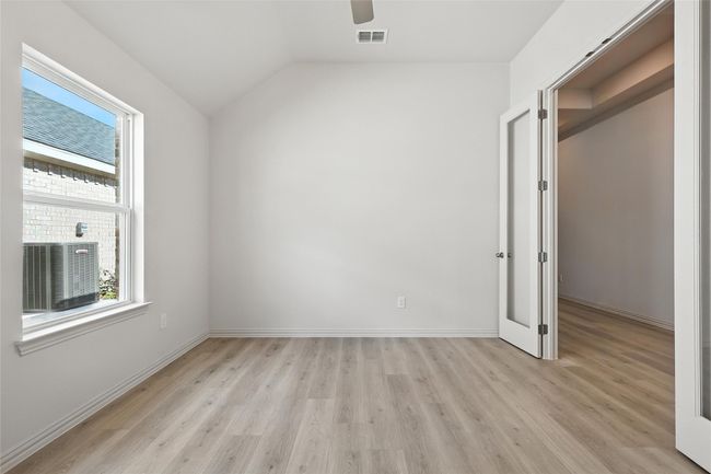 Unfurnished bedroom with multiple windows, light wood-type flooring, lofted ceiling, and ceiling fan | Image 16