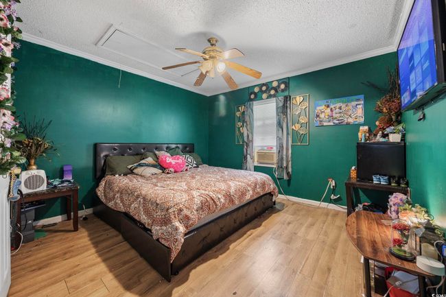 Bedroom featuring attic access, a textured ceiling, wood finished floors, crown molding, and ceiling fan | Image 12