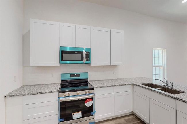 Kitchen with white cabinets, sink, backsplash, and stainless steel appliances | Image 15