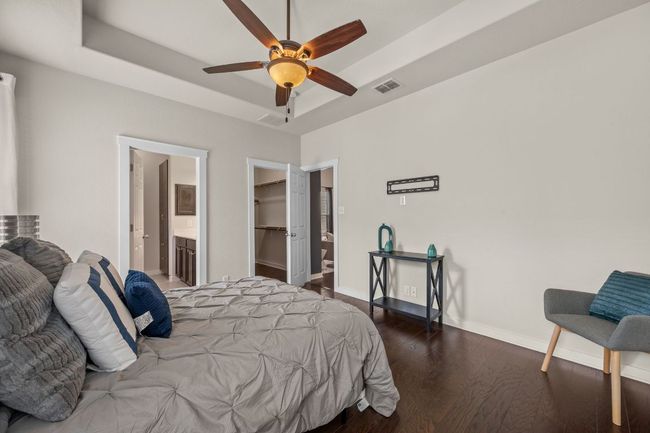 Bedroom featuring wood finished floors, a raised ceiling, baseboards, a walk in closet, and connected bathroom | Image 17