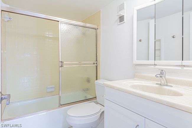 Full bathroom featuring combined bath / shower with glass door, toilet, and vanity with extensive cabinet space | Image 25