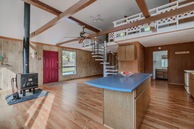 Kitchen with light hardwood / wood-style flooring, wooden walls, a wood stove, and beam ceiling | Image 23
