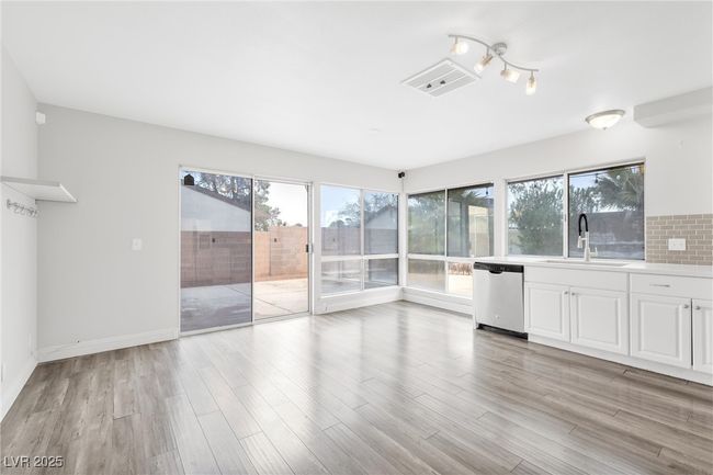 Unfurnished living room featuring visible vents, light wood-type flooring, baseboards, and a sink | Image 6