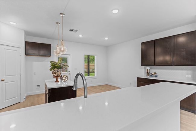 This view highlights the expansive center island with breakfast bar seating, sleek quartz countertops, and a deep undermount sink—ideal for both everyday convenience and effortless entertaining. **Image Representative of Plan Only and May Vary as Built**. | Image 10