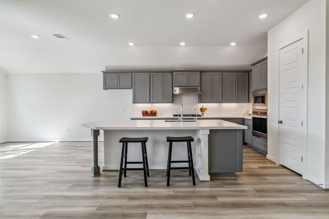 Kitchen featuring under cabinet range hood, stainless steel appliances, gray cabinetry, recessed lighting, and a center island with sink | Image 10