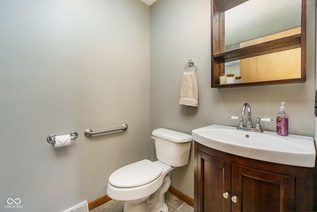 half bath with toilet, vanity, tile patterned floors, and baseboards | Image 24