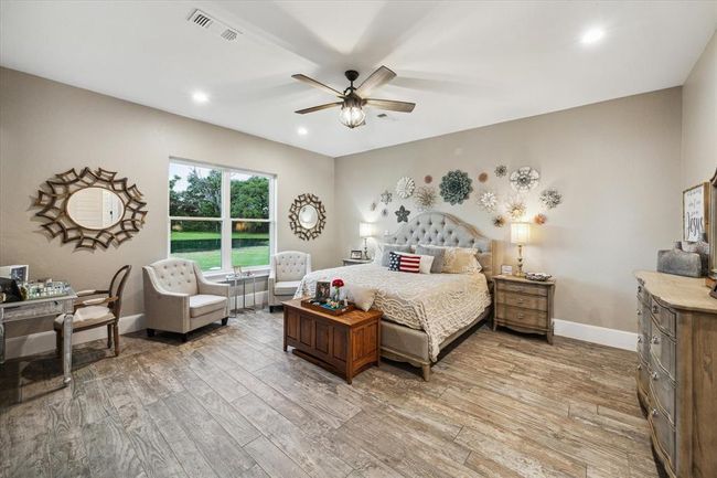 The in-law suite’s oversized primary bedroom features crown molding, a peaceful view of the pond and wildlife, and a cozy sitting area. Wheelchair accessible, it also includes two large walk-in closets with custom shelving, offering ample storage and easy organization. | Image 37