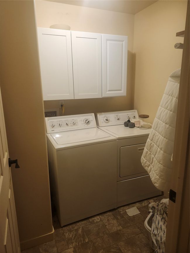 Washroom featuring stone finish flooring, cabinet space, and separate washer and dryer | Image 7