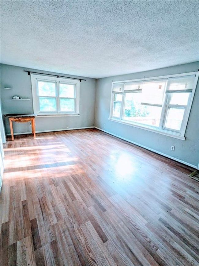 Unfurnished living room featuring wood finished floors, healthy amount of natural light, and a textured ceiling | Image 7