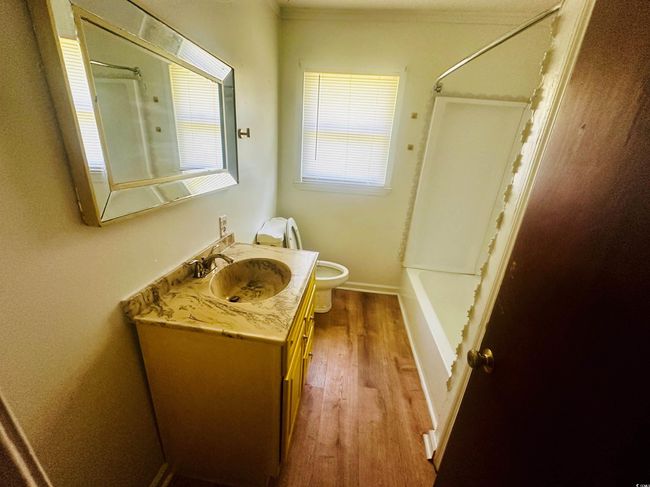 Bathroom with toilet, vanity, wood finished floors, shower combination, and ornamental molding | Image 18