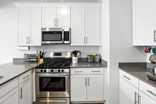 Kitchen featuring appliances with stainless steel finishes, white cabinets, and dark grey quarts countertops | Image 30