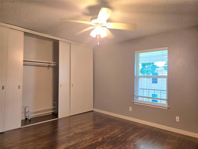 Bright bedroom featuring hardwood floors, a ceiling fan, ample natural light, and a spacious closet with sliding doors. | Image 7