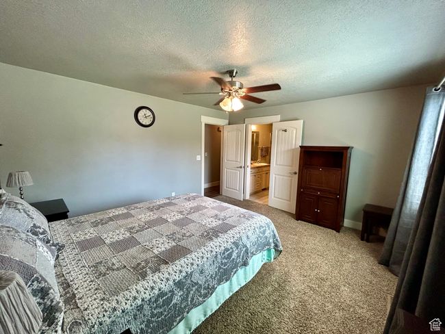 Bedroom with light carpet, baseboards, a textured ceiling, and ceiling fan | Image 14