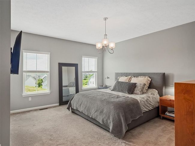 This spacious primary bedroom offers a serene retreat with soft, neutral carpeting and stylish gray walls that create a calming ambiance. | Image 15